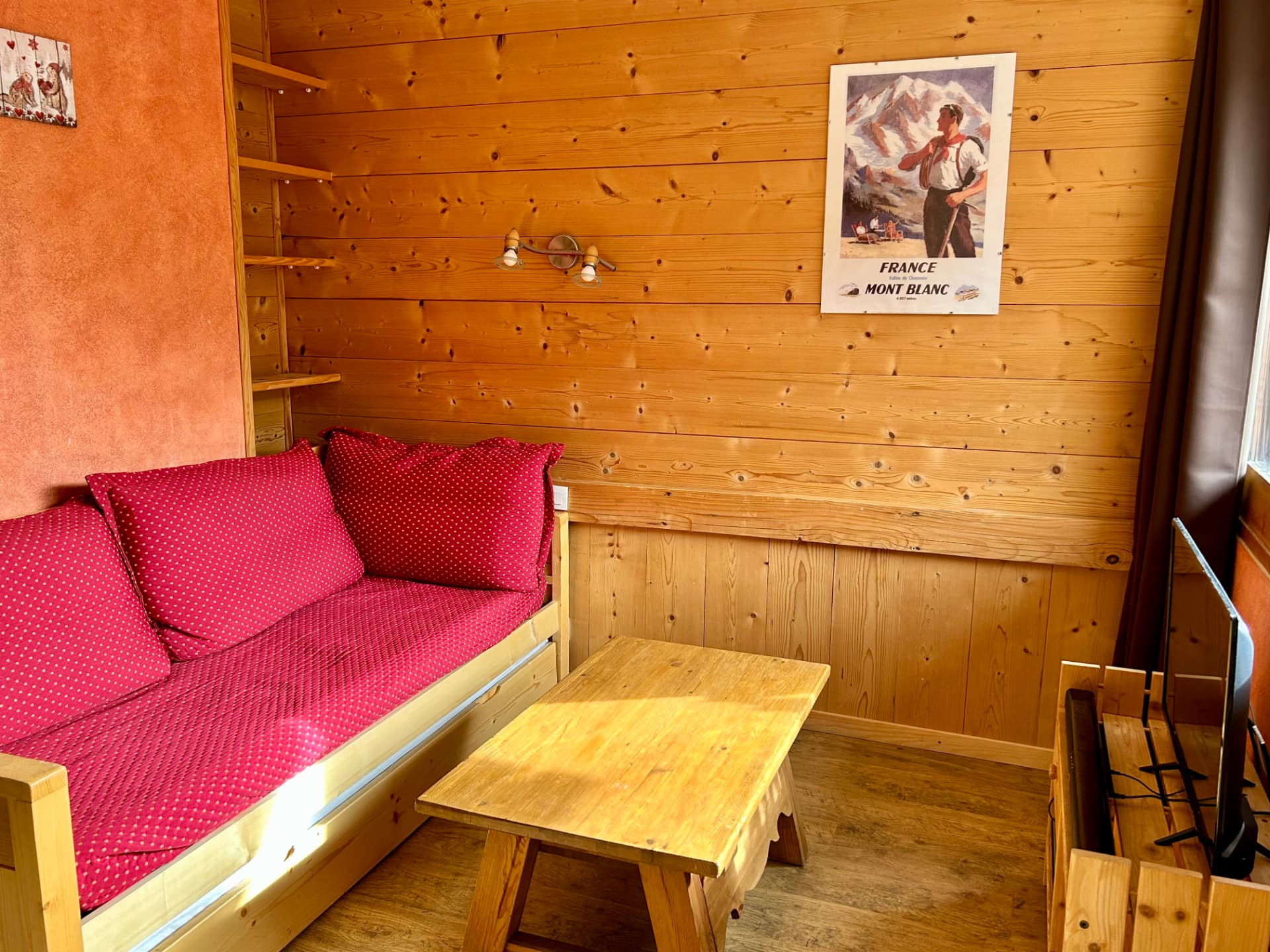 Salon en lambris avec banquette rouge à pois et table basse en bois